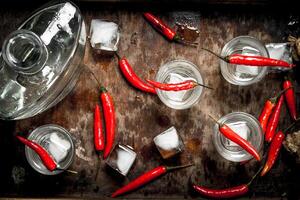 Vodka scatti con chili peperoni su un' di legno vassoio. foto