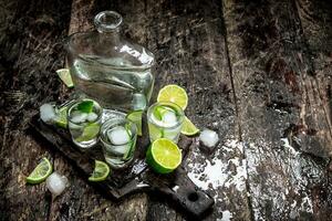 Vodka scatti con lime e ghiaccio su il tavola. foto