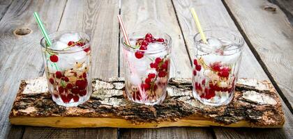 tre selvaggio ribes cocktail con ghiaccio su un' di legno tavolo. foto