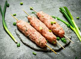 crudo kebab su di legno spiedini con verde cipolle. foto