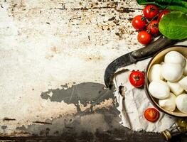 Mozzarella formaggio, pomodori, oliva olio e un vecchio coltello. foto