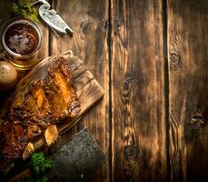 Maiale costolette grigliato con un' carne accetta e birra. foto