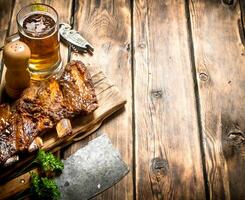 Maiale costolette grigliato con un' carne accetta e birra. foto