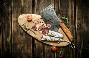 salame e un vecchio accetta con rosmarino. foto