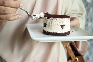 donne mangiare un' pezzo di cioccolato torta foto