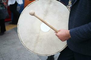 un' uomo colpire il antico tamburo con musicale strumento. foto