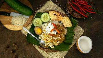 nasi liwet è un' indonesiano tradizionale cibo cucinato con Noce di cocco latte, pollo brodo, citronella e spezie così quello esso ha un' salato gusto e distintivo aroma. cetriolo e cracker siamo complementare. foto