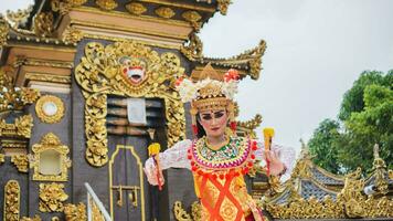 ragazza indossare balinese tradizionale vestito con un' danza gesto su balinese tempio sfondo con -Tenuto in mano fan, corona, gioielleria, e oro ornamento Accessori. balinese ballerino donna ritratto foto