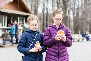 Due ragazze sorelle comprato torte nel un' cibo camion nel un' città parco e siamo andando per mangiare foto