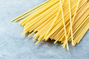 crudo lungo spaghetti su un' grigio calcestruzzo sfondo. mediterraneo cibo foto