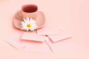 il concetto è rosa. rosa bevanda nel un' caffè tazza, scrittura lenzuola e crisantemo su un' rosa sfondo. copia spazio foto