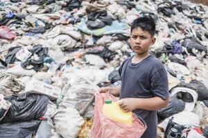 triste bambino su spazzatura scarico, ragazzo raccolta su spazzatura per saldi, concetto di povertà, bambino lavoro duro e faticoso e umano traffico. foto