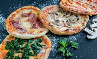 mini pizze con vari condimenti sulla tavola di legno foto