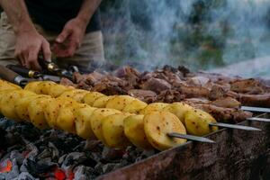 maschio mani cucinando carne su spiedini su barbecue griglia all'aperto foto