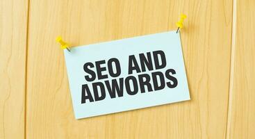 SEO e adwords cartello scritto su appiccicoso Nota appuntato su di legno parete foto