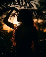 silhouette di un' donna in piedi nel davanti di palma alberi a tramonto generativo ai foto