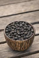 organico kampot essiccato in grani di pepe nero in una tradizionale ciotola di legno in cambogia foto