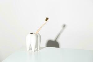 eco-friendly bambù spazzolino nel un' a forma di dente In piedi. consapevole consumo e dentale cura concetto. foto