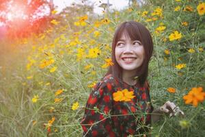 bellissimo minore asiatico donna trentadue denti sorridente viso con felicità emozione in piedi nel giallo cosmo fiore campo foto