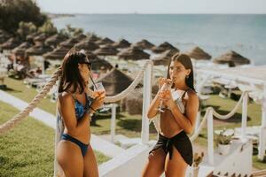 sorridente giovane donne nel bikini godendo vacanza su il spiaggia foto