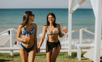 sorridente giovane donne nel bikini godendo vacanza su il spiaggia foto