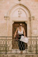 femmina turista con città carta geografica di il Chiesa san Francesco dassisi nel Ostuni, Italia foto