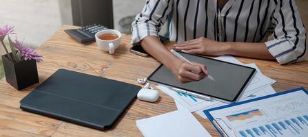 mani di donna che tengono la penna stilo e lavorano su digitale nero foto