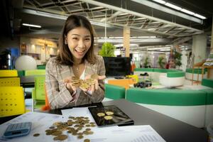 riuscito asiatico donna d'affari è mostrando sua proprio bitcoin con un' Sorridi su sua viso nel sua ufficio. foto