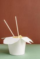 scatola di carta wok aperta con noodles e bacchette per il design mock up foto