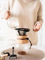 donna che prepara il caffè nella caffettiera, versando acqua calda nel filtro