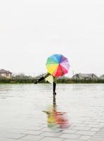 donna con ombrello colorato che balla sotto la pioggia foto
