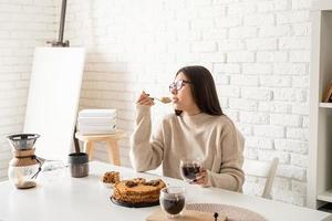 donna seduta al tavolo bianco, mangiando torta e bevendo caffè foto