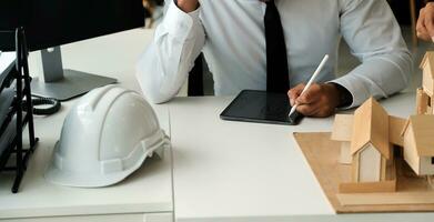 costruzione e struttura concetto di ingegnere o architetto incontro per progetto Lavorando con compagno e ingegneria utensili su modello edificio e planimetria nel Lavorando luogo, contrarre per tutti e due aziende. foto