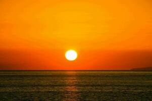 il sole ambientazione al di sopra di il oceano foto