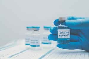 mano del medico in guanti blu che tengono coronavirus, vaccino covid-19 foto