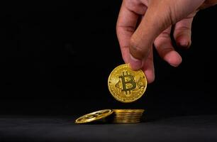 vicino su di mano hold d'oro bitcoin, bitcoin con nero sfondo. in linea shopping e crypto moneta concetto. foto