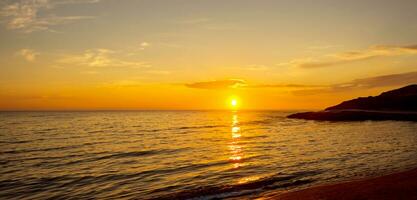 spiaggia mare sera a tramonto con rocce e colline arancia cielo foto