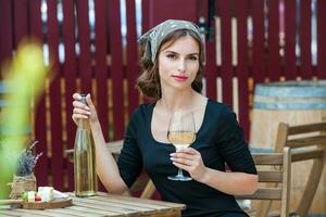 bellissimo giovane donna potabile bianca vino su il terrazza di un' ristorante. rilassante dopo opera con un' bicchiere di vino. singolo donna avendo divertimento. foto