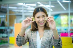 bellissimo asiatico attività commerciale donna tenuto un' oro moneta nel sua mano con un' Sorridi su sua viso. foto