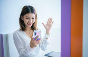 bellissimo asiatico attività commerciale donna è saluto i clienti al di sopra di il Telefono con un' Sorridi nel sua ufficio, digitale marketing. foto