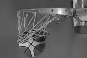pallacanestro palla caduta in il cestino su un' nero sfondo foto