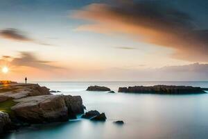 un' uomo sta su un' roccia prospiciente il oceano a tramonto. ai-generato foto