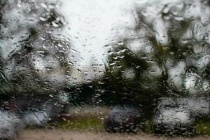 luminosa acqua su il auto finestra, dopo pioggia sera, nel il parcheggio, prendere avvicinamento fotografia, colore nero e grigio sfondo sfocato e paesaggio. foto