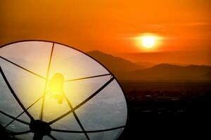 vicino su, satellitare piatto comunicazione tecnologia Rete per un' villaggio nel il campagna. cielo oro e tramonto su il valle foto