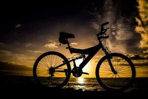 un' bicicletta è staglia contro il tramonto a il spiaggia foto