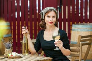 bellissimo giovane donna potabile bianca vino su il terrazza di un' ristorante. rilassante dopo opera con un' bicchiere di vino. singolo donna avendo divertimento. foto