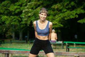 sportivo giovane donna nel abbigliamento sportivo fare allungamento esercizi all'aperto. ritratto di un' giovane ragazza fare sport nel il parco. foto