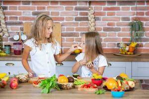 Due poco ragazze nel il cucina con fresco verdure. salutare cibo concetto. contento sorelle. foto