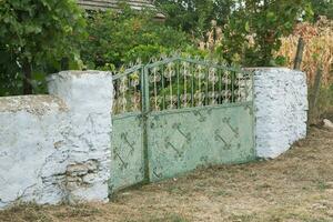 il cancello per il Casa è decorato con un' modello di metallo. vecchio abbandonato Casa nel il villaggio vecchio ferro cancello nel il cortile di un' nazione Casa. verde metallo cancello. foto