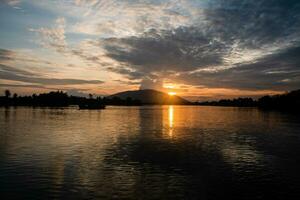 notte naturale scena, bene notte, d'oro leggero a partire dal il sole era andando fuori uso, dietro a il montagna Là era ancora un' suggerimento di d'oro luce. il leggero riflessi a partire dal il scintillante fiume. barca nel fiume foto